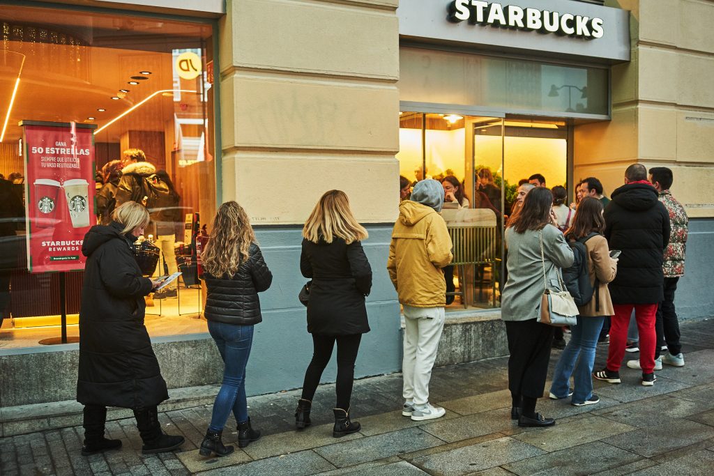 Varias personas hacen fila para entrar en la nueva tienda de Starbucks en Gran Vía